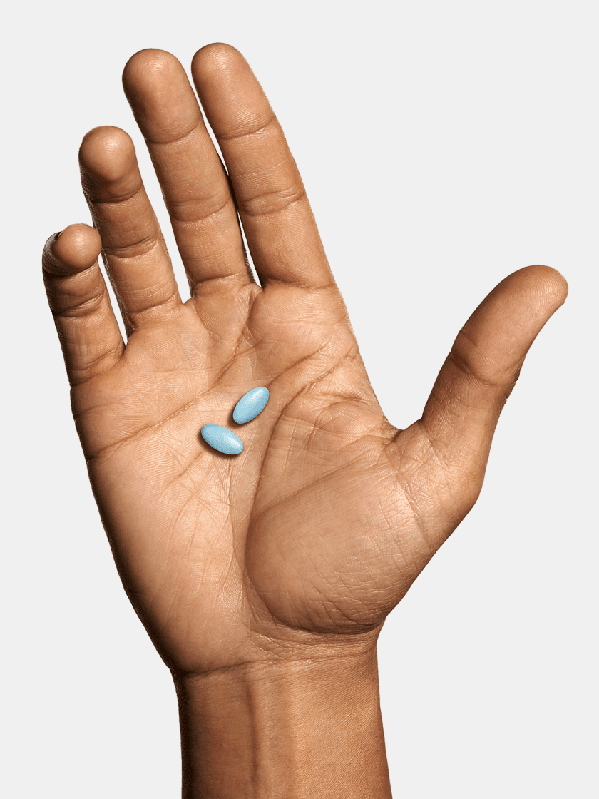 Hand holding two blue pills